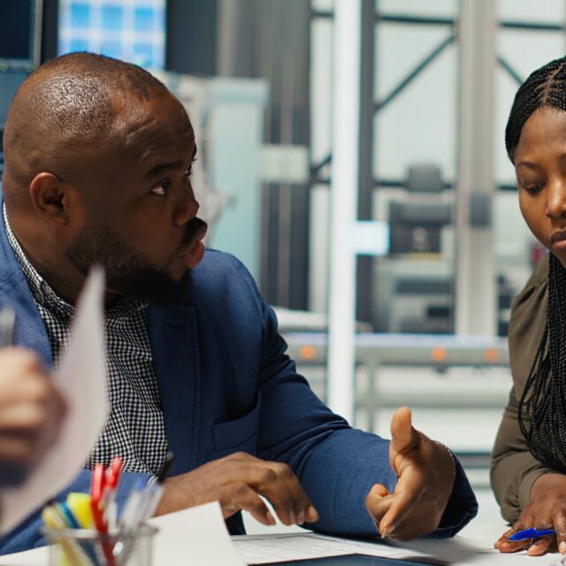 Factory engineering team look at assembly lines designs, working to increase energy output. Photovoltaics plant experts brainstorm innovative solar cell prototypes, looking over schematics, camera B