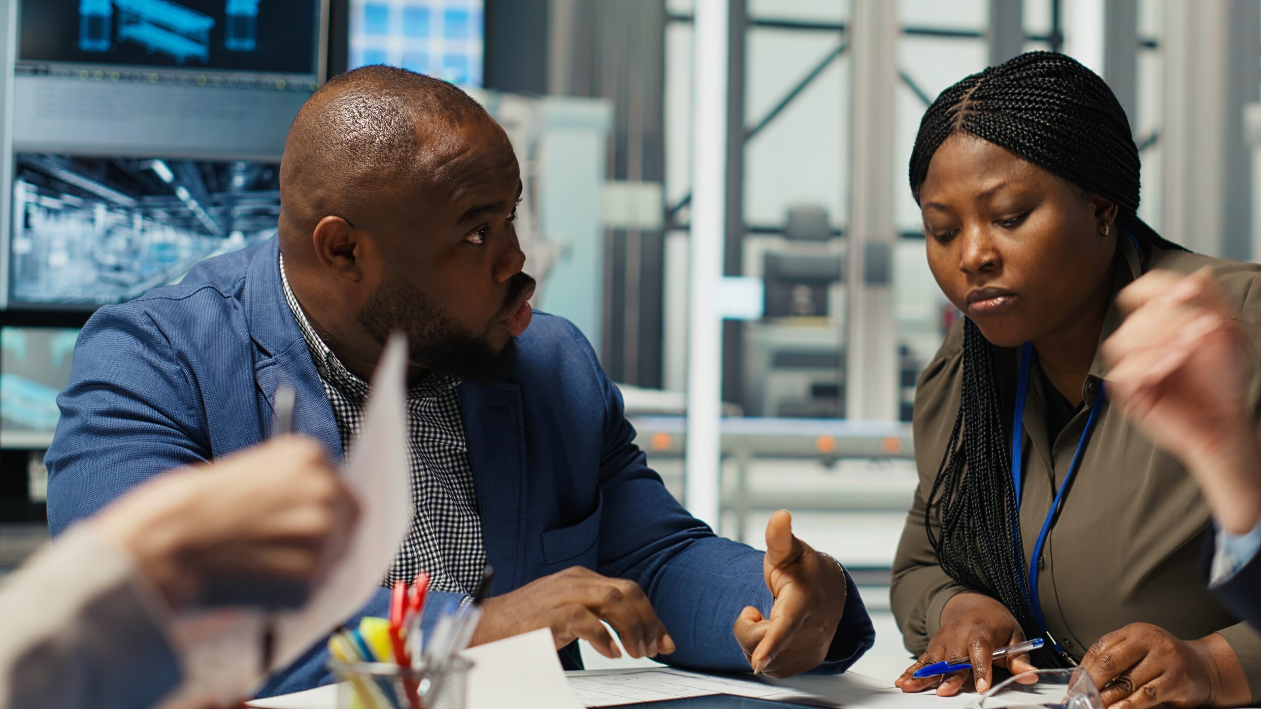 Factory engineering team look at assembly lines designs, working to increase energy output. Photovoltaics plant experts brainstorm innovative solar cell prototypes, looking over schematics, camera B